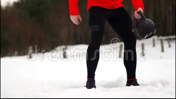 有魅力的运动健将在冬季和雪天的户外健身中进行水壶钟运动视频的预览图