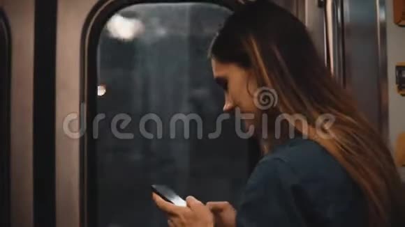 美国芝加哥乘地铁的年轻快乐女人的肖像微笑的女性在日落时使用智能手机视频的预览图