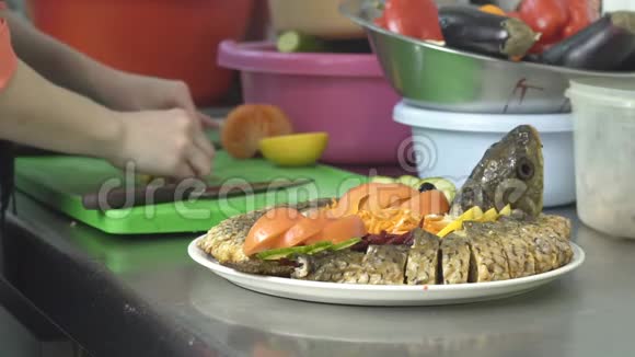 厨师用柠檬和蔬菜装饰烤鱼慢动作美食视频的预览图