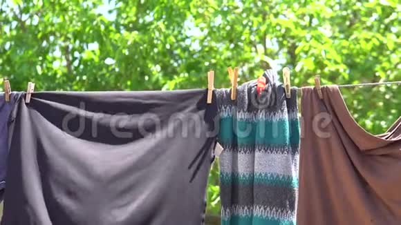 清洁洗过的衣服挂在电线上挂在衣服钉上模糊了村庄的春天自然背景视频的预览图