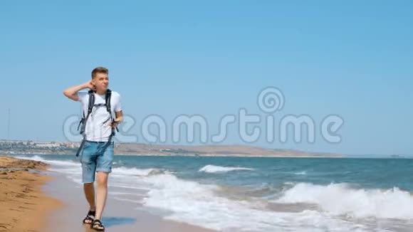 一个年轻人走在沙滩上用手机拍了一只海鸥视频的预览图
