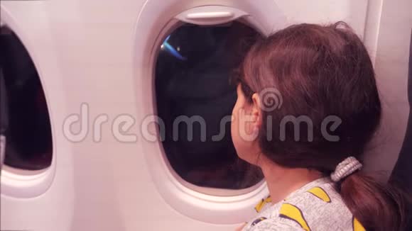 航空飞机概念年轻的少女在飞行时看着飞机在夜间的窗口飞行年轻乘客视频的预览图