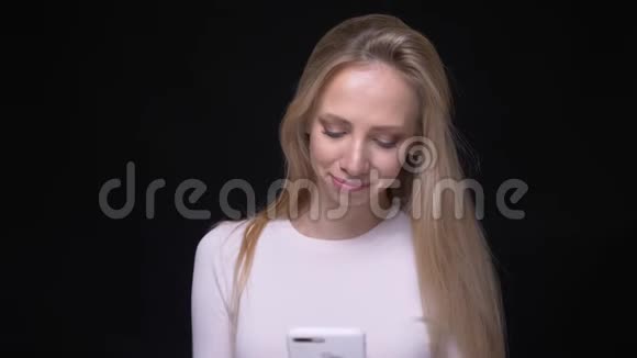 年轻漂亮金发女性的特写照片她用手机微笑着看着镜头背景与镜头隔绝视频的预览图