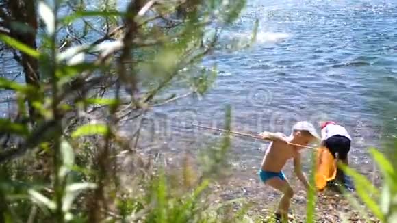 三个孩子站在一条山河的岸边他们向河里扔石头兄弟俩过暑假视频的预览图