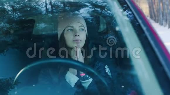 女人在树林里的车里暖手冬季寒冷概念视频的预览图