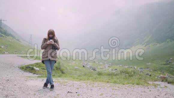 一个年轻的女人徒步旅行者用相机爬上山脉使用智能手机罗马尼亚喀尔巴阡山脉视频的预览图