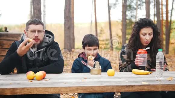 妈妈爸爸和孩子在餐桌旁的树林里坐在一起享受美食正面观点视频的预览图