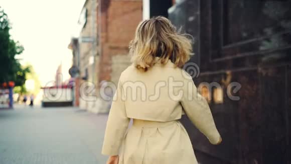 微笑的年轻女子穿着时髦的外套走在街上转向相机看着她的慢镜头视频的预览图
