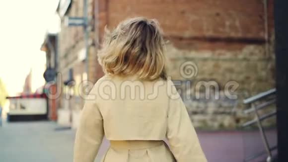 慢镜头肖像迷人的金发女孩走在街上微笑和看相机快乐的人视频的预览图