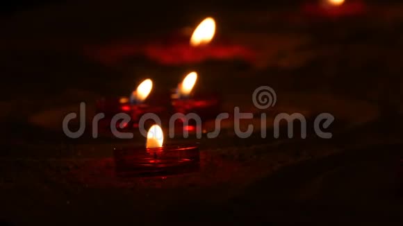 在一个天主教的寺庙里红色的圆形燃烧的葬礼蜡烛在沙子上黑暗中的烛光视频的预览图