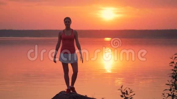 一位漂亮的年轻女子正在湖畔练习姿势视频的预览图