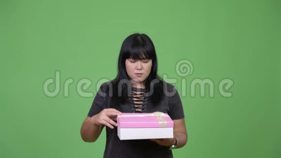 美丽的超重亚洲女人打开礼品盒看上去很惊讶视频的预览图