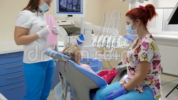 由助理牙齿矫正师为儿童在牙科椅上用特殊设备治疗牙齿做准备视频的预览图