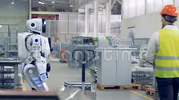 一个人在工厂激活机器人一个工人打开一个机器人让它拉一辆装有金属片的重型手推车视频的预览图