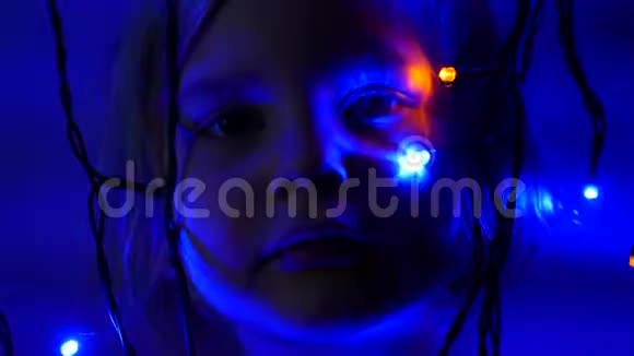 小女孩在黑暗的石榴石灯附近触摸五颜六色的球体视频的预览图