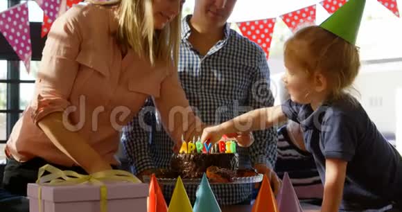 母亲和儿子在家里装饰生日蛋糕视频的预览图