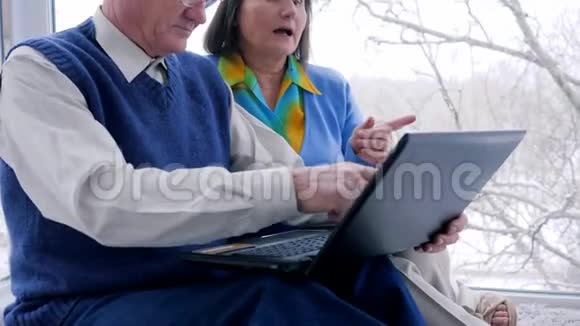网上购物休闲时间有电脑的老年夫妇坐在网上微笑视频的预览图