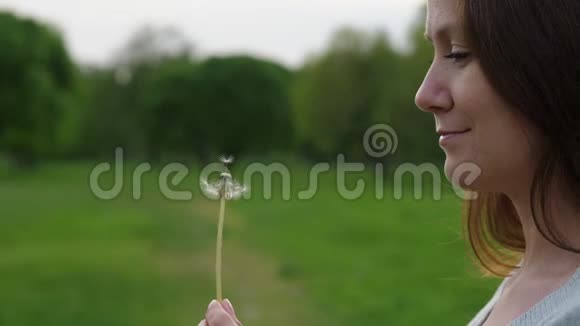 女人在蒲公英种子头上摸着手指花吹着小花飞走了视频的预览图