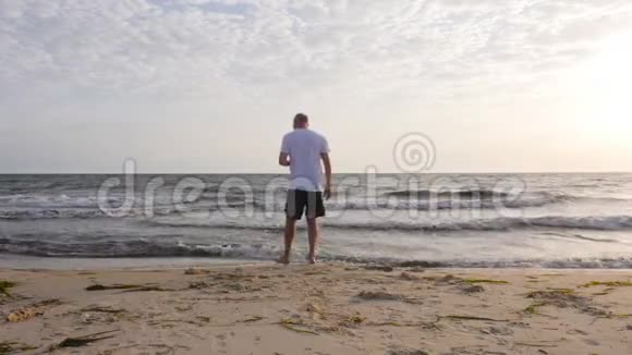 成年男子在沙滩上散步在海边看东西视频的预览图