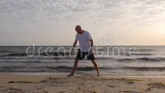 男子站立瑜伽姿势utthitaparvakonasana的背景波海滩视频的预览图