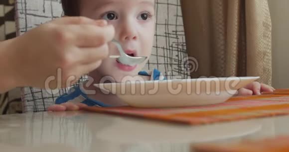 母亲在家里用小勺子给婴儿食物孩子吃得很心甘情愿4k视频的预览图