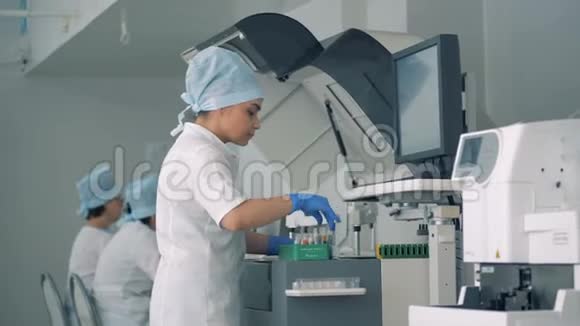一名实验室工作人员将试管转移到生化分析仪中视频的预览图