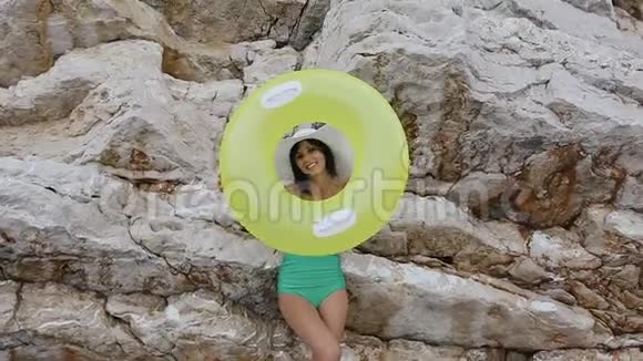 穿着泳衣和帽子的漂亮女孩在她手上做了一个充气浮球圈然后看着里面视频的预览图