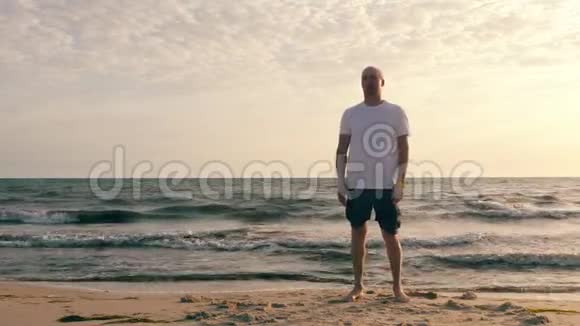 海边晨练时做呼吸运动的成年男子视频的预览图