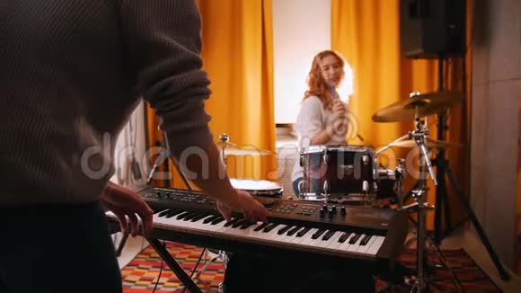 重复男人在键盘上演奏女鼓手在后台演奏背光灯把注意力集中在手上从后面看视频的预览图