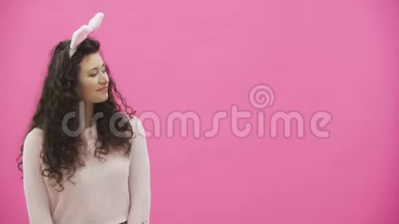 粉红色背景的年轻性感夫妇头上戴着黑黑的耳朵在这段时间里男人把一个软玩具和一只野兔送给视频的预览图