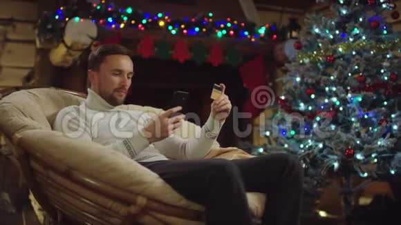 圣诞夜使用手机和信用卡在线购物的成年男性顾客视频的预览图
