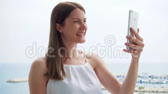 一位正在度假的妇女通过移动信使应用程序在阳台上与朋友视频聊天视频的预览图