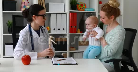 医生带着孩子在办公室给母亲展示木制模型视频的预览图