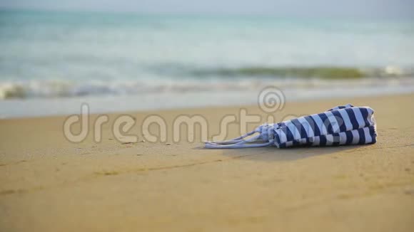 沙滩包躺在沙质的海岸上面对模糊的无边无际的大海和海浪视频的预览图