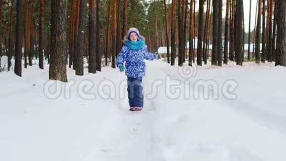 一个快乐的女孩在白雪覆盖的森林里沿着小路奔跑视频的预览图