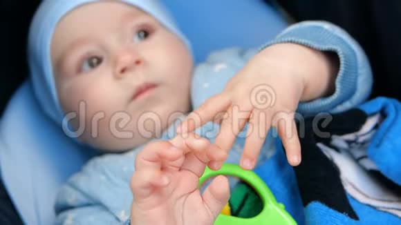 小男孩躺在婴儿车上用她的小手拿着玩具视频的预览图