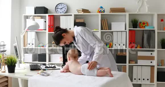年轻的医生在办公室里和婴儿一起玩并在摄像机上显示拇指视频的预览图