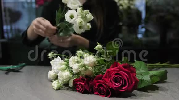专业的花艺师把白色和红色的玫瑰花剪在桌子上女人的手特写视频的预览图