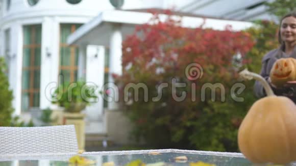 女人把南瓜杰克带到院子里的桌子上准备秋天的万圣节晚会视频的预览图