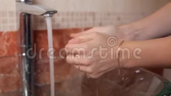 一个年轻的女孩站在浴室里用透明的水盆洗手视频的预览图