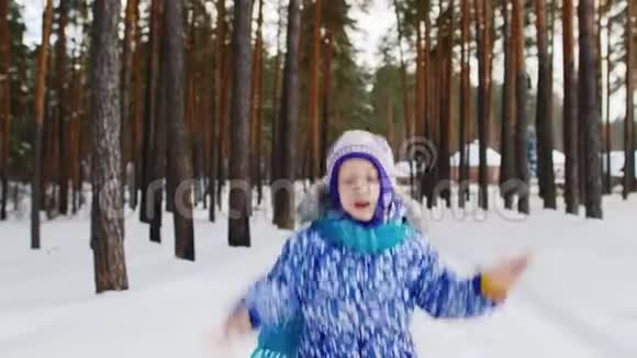 一个快乐的女孩在白雪覆盖的森林里沿着小路奔跑视频的预览图