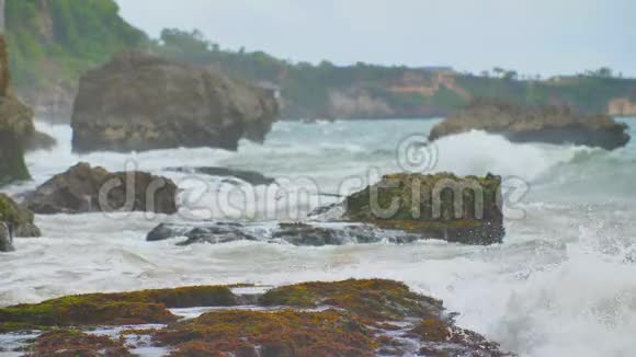 在巴厘岛附近缓慢的石质和岩石海岸有强烈的波浪和风泰格旺吉海滩印度尼西亚视频的预览图