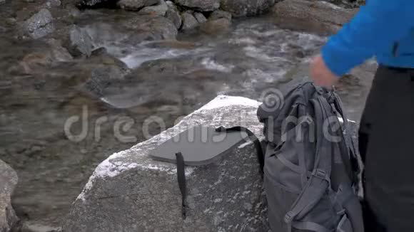 旅行者从背包里拿出一个锅和一个燃气燃烧器来做饭他要在一个美丽的地方休息视频的预览图