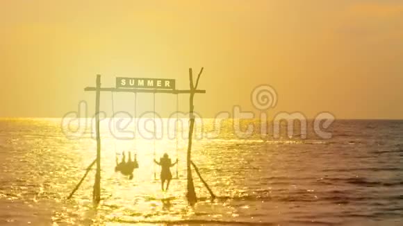 4K幸福夫妇的剪影喜欢在日落时随着秋千在海上摇曳暑假快乐视频的预览图