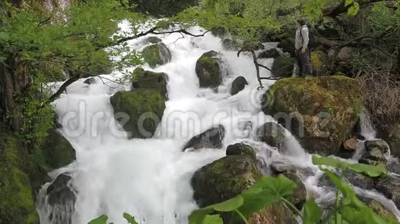 这个人在潮湿的热带森林里欣赏瀑布暴风骤雨的河流干净的水上升泡沫视频的预览图