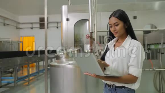 一位女工程师拿着一台笔记本电脑在饮料制造业看相机的肖像视频的预览图