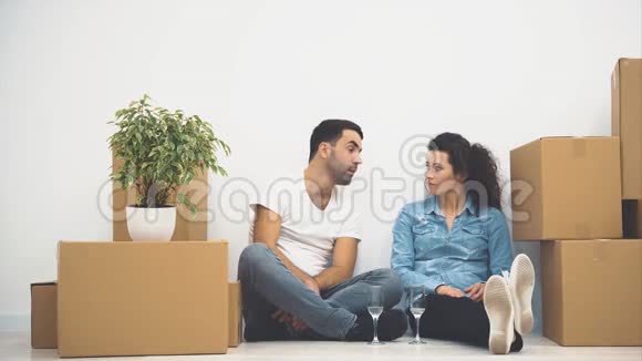 幸福的一对夫妇正坐在地板上拿着一杯白葡萄酒说话行动4K视频的预览图