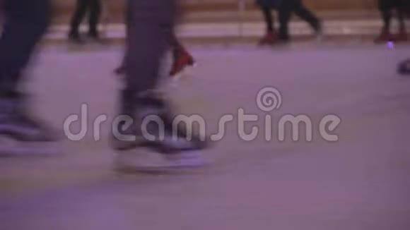 人们在户外溜冰场滑冰冬季夜晚的滑冰运动员庆祝新年和圣诞节从腿上看视频的预览图