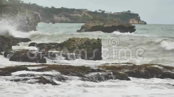 在巴厘岛附近缓慢的石质和岩石海岸有强烈的波浪和风泰格旺吉海滩印度尼西亚视频的预览图