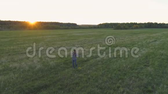 日落时分女人走在田野上手里拿着花手臂伸向两边视频的预览图